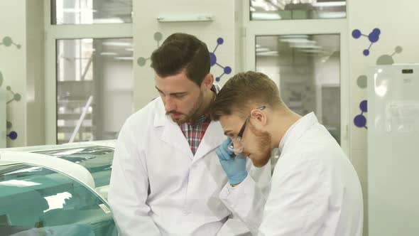 Two Young Laboratory Assistants Discuss the Nuances of Their Workflow alt