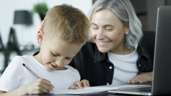 Close Up Mother Helping Son With Homework Sitting At Desk In Bedroom