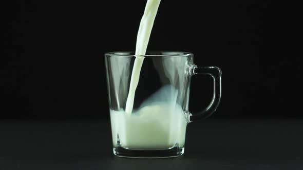 Milk Pouring Into Glass Mug Close Up Isolated on Black Background Slow Motion alt