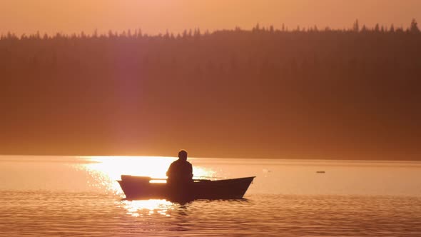 Man Sitting in a Boat on River and Fishing on Sunset alt