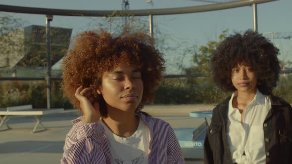 Two Mixed Race Black Woman with Huge Afro Hair Outdoors Watching To the Camera