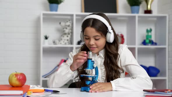 Amazed Kid in School Uniform and Headphones Use Microscope Biology