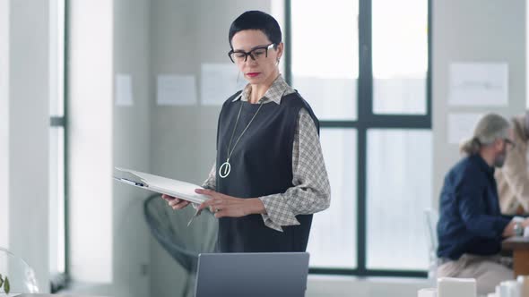Elegant Business Lady Walking in Office and Checking Documents alt