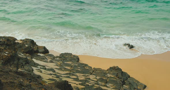 Perfectly Clean Ocean Water Wild Fine Yellow Sand Beach and Black Stones of Coast on Tropical Island
