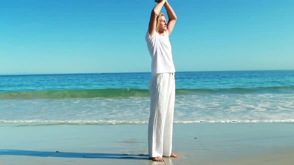 Man performing yoga at beach alt