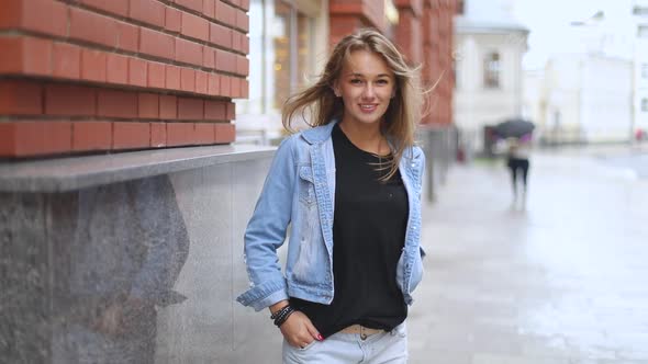 Portrait of beautiful caucasian blonde laughing girl on the street and the wind moving her hair