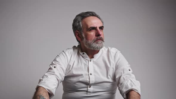 50s Caucasian Grey Haired Man Looking Away with Serious Expression Then Looking to the Camera alt