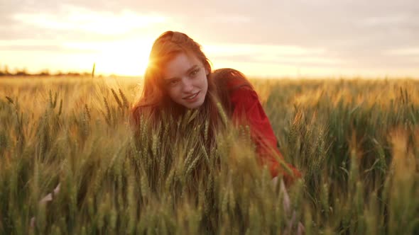 Slow Motion of Beautiful Happy Romantic Redhead Girl in Red Dress Hugging Wheat Ears and Laughing