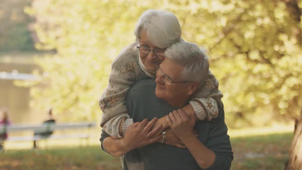 Happy Old Couple Hugging in Park. Senior Man Flirting with Elderly Woman. Romance at Old Age Dancing alt