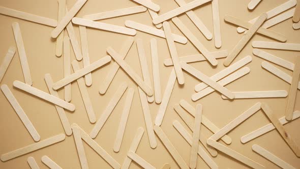 Wooden Popsicle Sticks Scattered on Top of a Beige Background