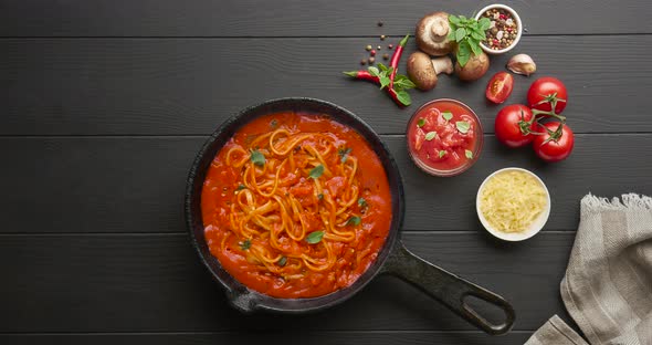 Cooking homemade Italian pasta spaghetti with tomato sauce in cast iron pan
