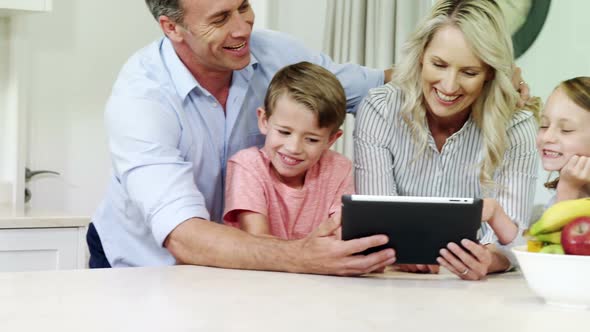 Smiling family using digital tablet together in living room alt