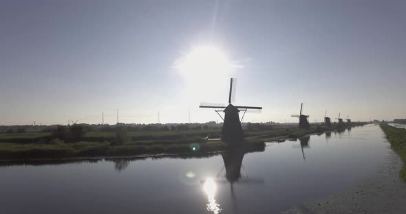 A drone shot panning right, around Dutch Windmills during sunrise alt