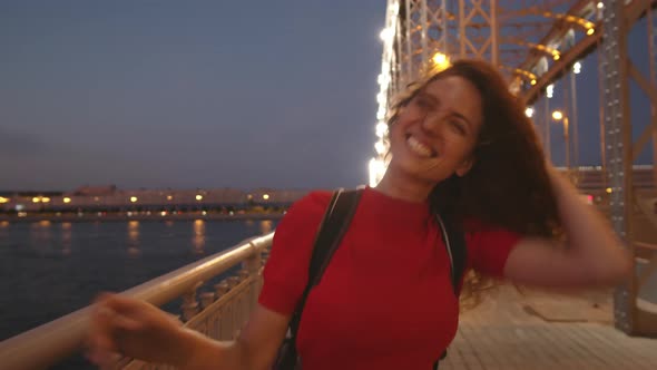 Ecstatic Woman Laughing and Walking along Bridge alt