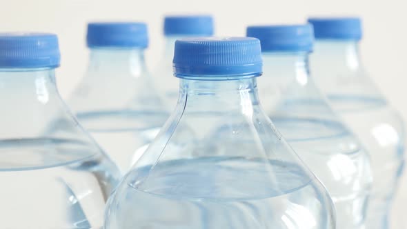 Bottled water in a row close-up 4K 2160p 30fps UltraHD tilting footage - Blue caps on PET containers alt