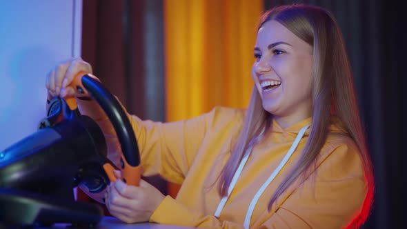 Girl playing with steering wheel. Young pro gamer girl playing car racing alt