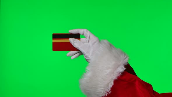 Santa Claus Hands in Red Suit and White Gloves are Holding a Bank Card alt