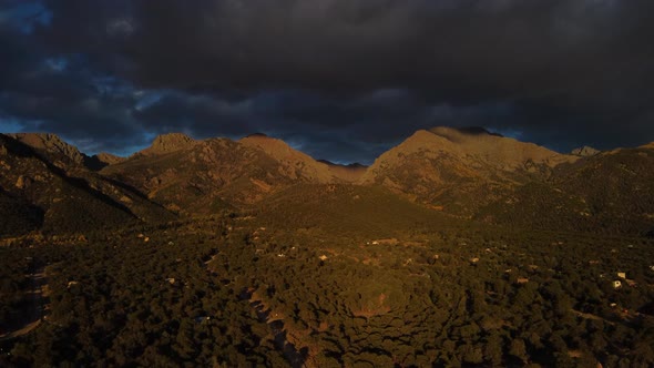 Dark and stormy clouds over the Colorado Rockies while the sun sets, Aerial alt