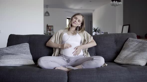 Front View of Expectant Mother Resting on Sofa at Home alt