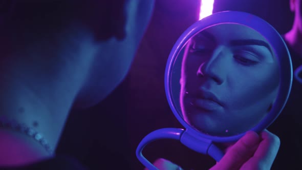 Drag Artist  Young Man Applying Base Color on His Eyes  Blue and Purple Neon Lighting alt