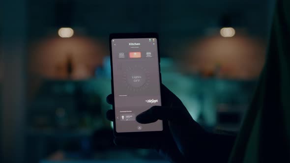 Man Holding Smartphone with Active Smart Home Application Switching on Light alt