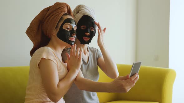 Two Girls with a Towel on Their Head and a Black Skin Care Mask alt