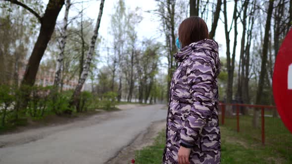 The End of the Pandemic and Virus Spread. A Mom in a Mask Near the Red Stop Sign. Healthcare and