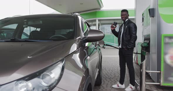 Handsome American Man Drinking Coffee Near His Car At The Gas Station alt