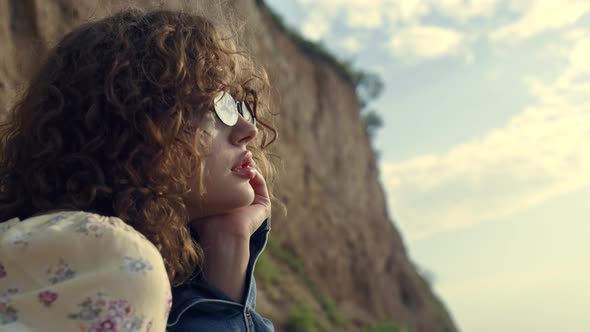 Dreamy Woman Portrait Sitting in Sunglasses on Seashore alt