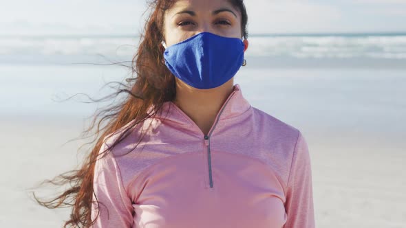 Portrait of mixed race woman wearing face mask at the beach alt