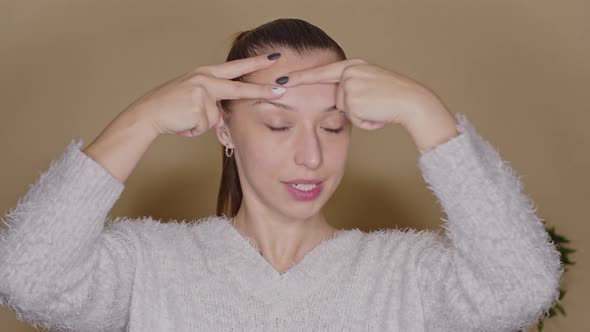 Positive Female Vlogger Doing Face Lifting Exercises on Forehead, Blogging