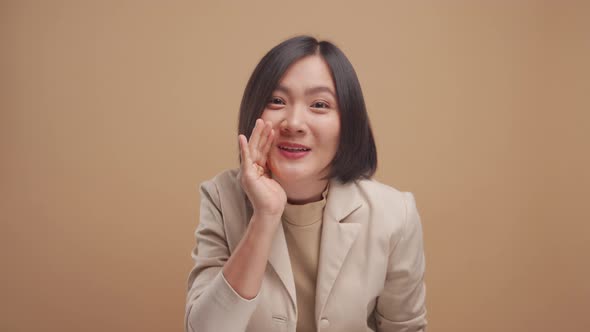 Asian business woman happy smiling make a whisper gesture and looking at camera isolated