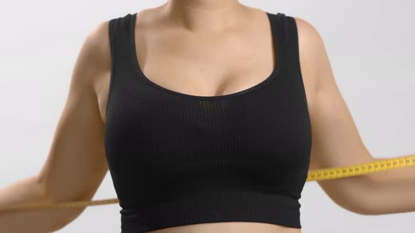 Caucasian Young Woman in Black Sport Bra Measuring Her Breast with a Tape
