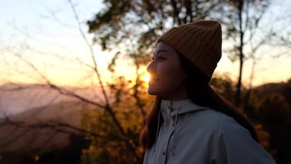 Slow motion of a female traveler standing on mountain peak and looking at a beautiful nature view