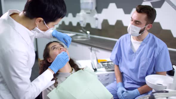 Dentist and Dental Assistant Examining Teeth of Female Patient alt