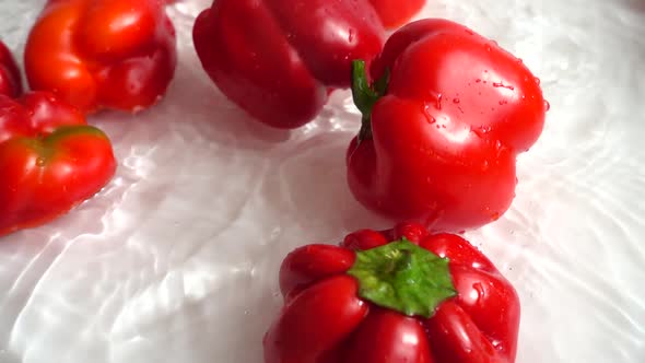 The bell sweet peppers falling into the water. Slow motion. alt