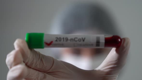 A young woman doctor holds positive coronavirus test. Close up shot.	 Coronavirus icon. alt