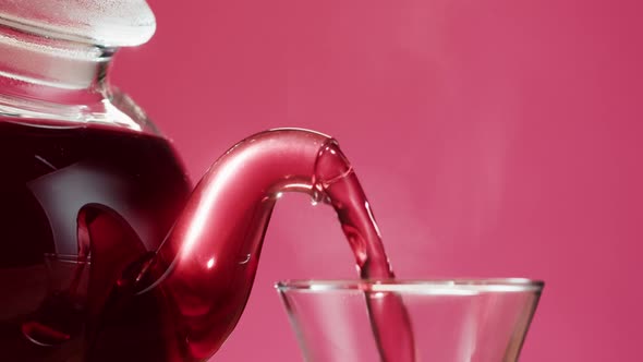 Pouring Red Fruit Tea on Pink Background alt