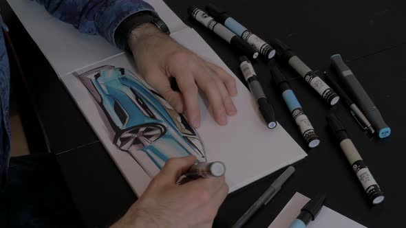 Hands drawing a blue car alt