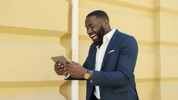 Successful African Businessman Walking with Tablet Computer on Urban Street alt