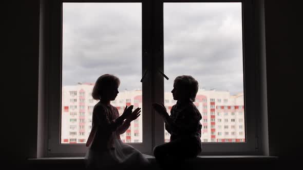 Silhouette of Children Playing Hand on Window Sill. alt