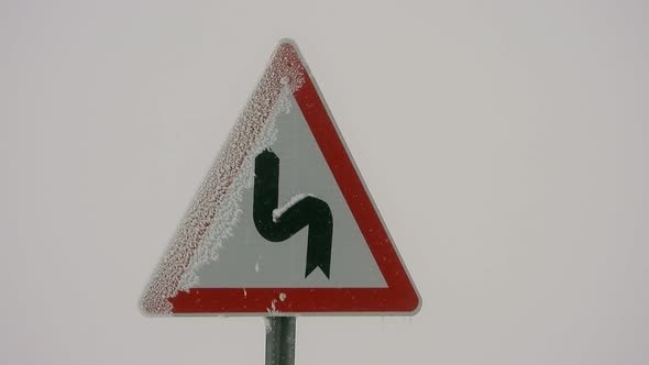 Highway Sign of Mountain Winding Road in Heavy Snowfall Weather
