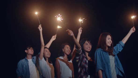 Group of Asian friends teenagers play firecracker dancing have fun enjoy party with happy at night.
