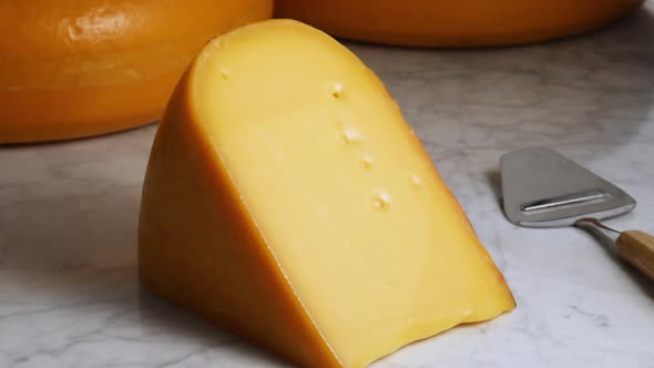 Large piece of traditional mature Dutch Gouda cheese on a marble table  alt