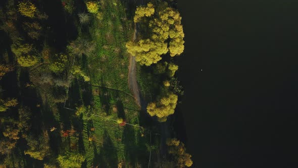 U Turn Flight Over An Autumn Park Located On The Shore Of A Large Lake. alt