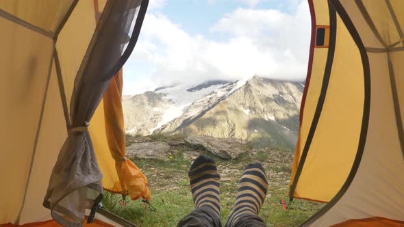 Person Lies in Yellow Tent and Moves Feet in Colored Socks alt