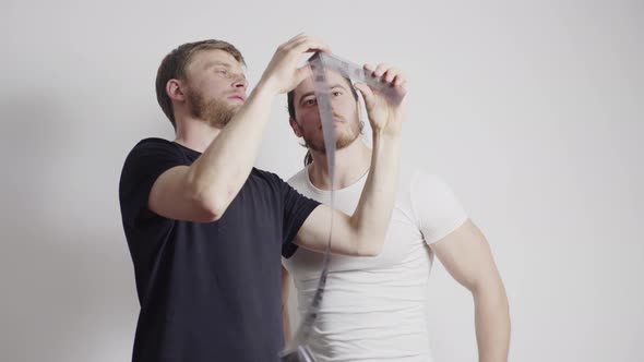 Two Guys are Standing in a White Room Looking at the Filmstrip