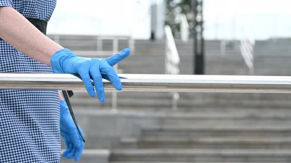Way of Transmitting Viruses and Diseases Covid-19. a Girl in Gloves Touches Railings and Handrails alt