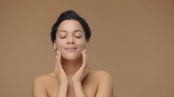 Beauty Portrait of Young African American Woman Striking Face with Fingers and Giving Gentle Skin alt
