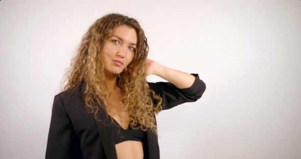 Portrait of a Smiling Curly-haired Girl Who Is in the Studio on a White Background, Wearing a Black alt